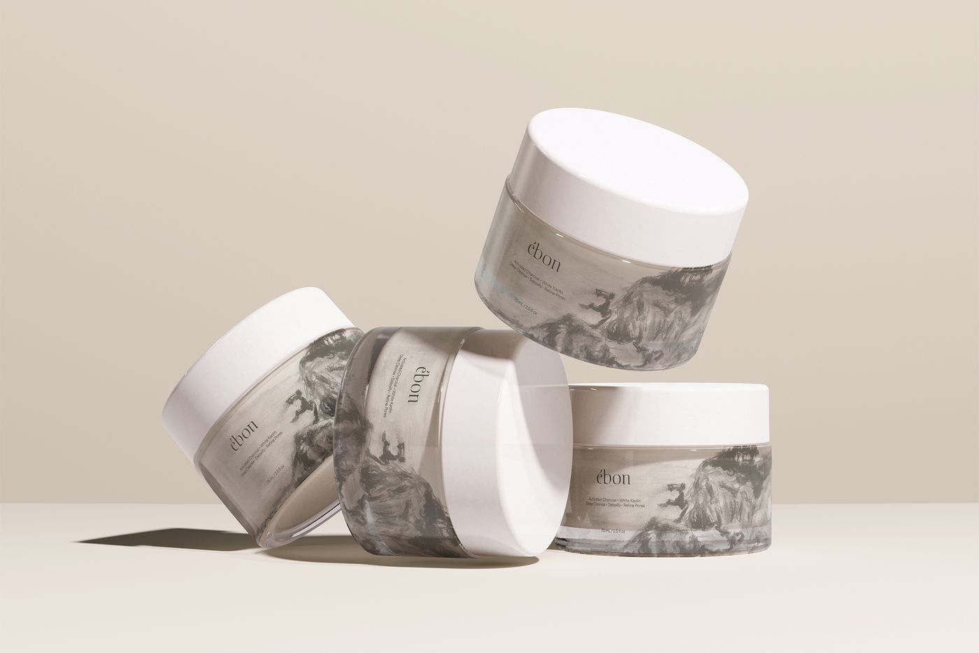 Ébon clay mask jars stacked and tilted on a neutral surface.